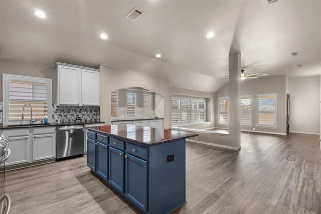 a kitchen with stainless steel appliances granite countertop a stove and a wooden floors