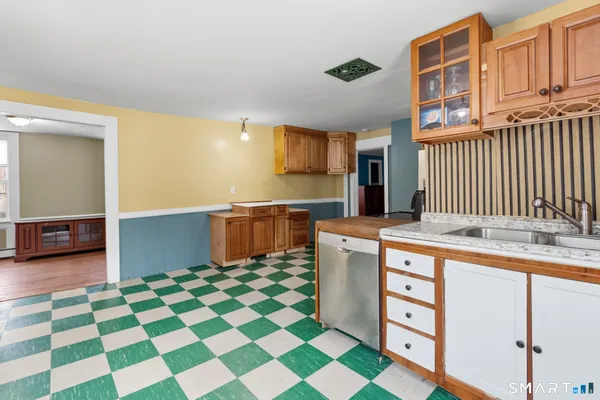 a kitchen with stainless steel appliances kitchen island granite countertop a sink and a black white checkered floor