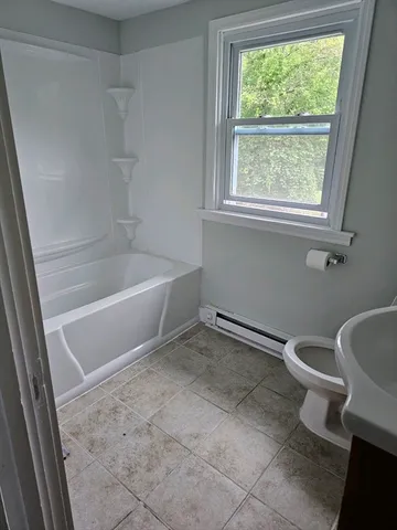 a white bath tub sitting next to a toilet