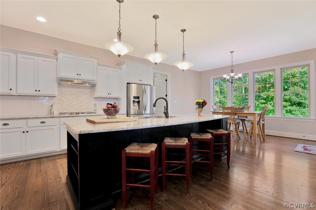 16106 Alsdell Road Midlothian, VA 23112 - Photo 5 of 46 a kitchen with stainless steel appliances granite countertop a stove a sink a refrigerator a dining table and chairs with wooden floor