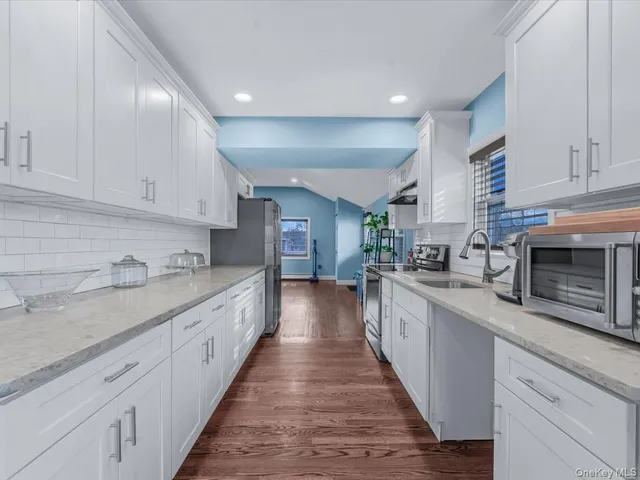 a large kitchen with stainless steel appliances granite countertop a lot of counter space and wooden floors