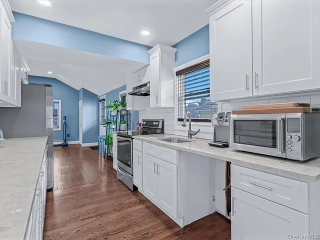 a kitchen with granite countertop white cabinets and white appliances