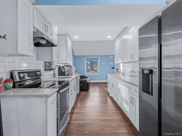 a kitchen with stainless steel appliances granite countertop a refrigerator a stove and a sink