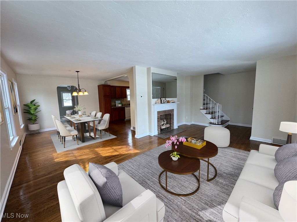 904 Trebisky Road Cleveland, OH 44121 - Photo 5 of 11 Living area featuring a chandelier, a brick fireplace, stairs, and dark wood-style flooring