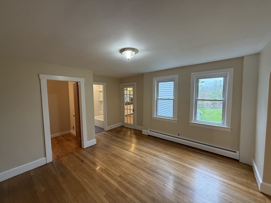84 Emerald Road, Unit 1 Rutland, MA 01543 - Photo 4 of 22 an empty room with wooden floor and windows