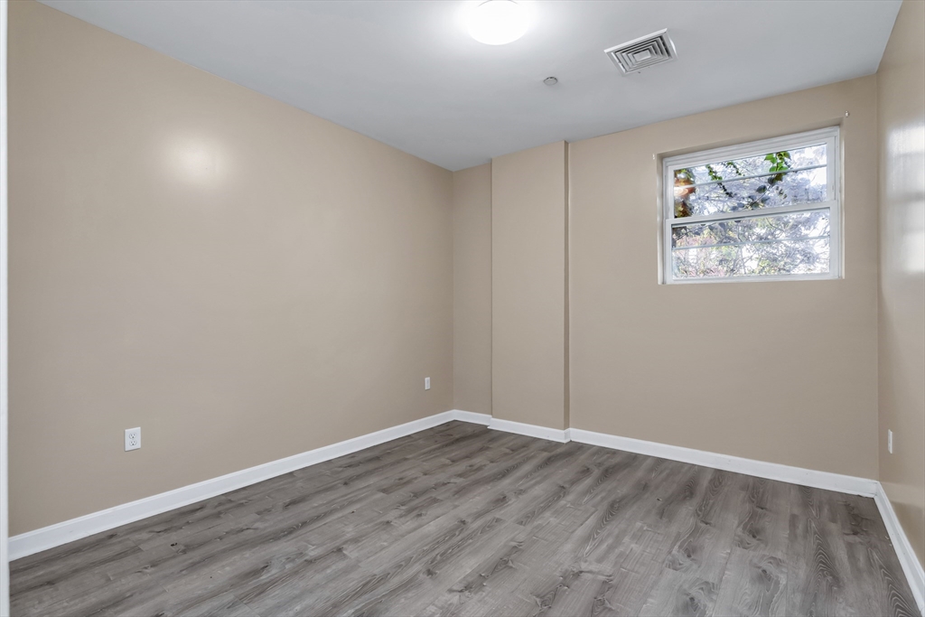 202 Broadway, Unit 23 Lawrence, MA 01840 - Photo 11 of 15 an empty room with wooden floor and window