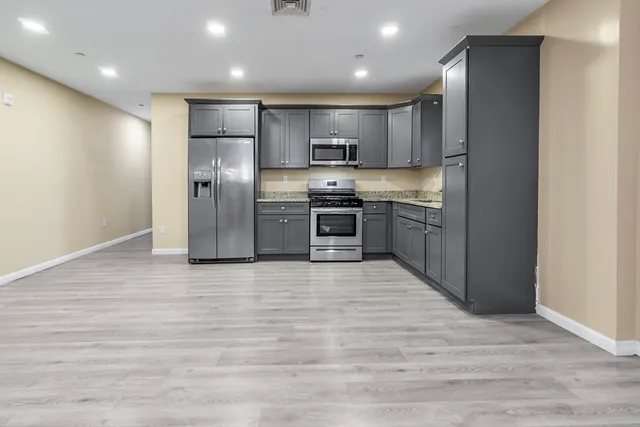 a large kitchen with stainless steel appliances granite countertop a refrigerator and a stove top oven