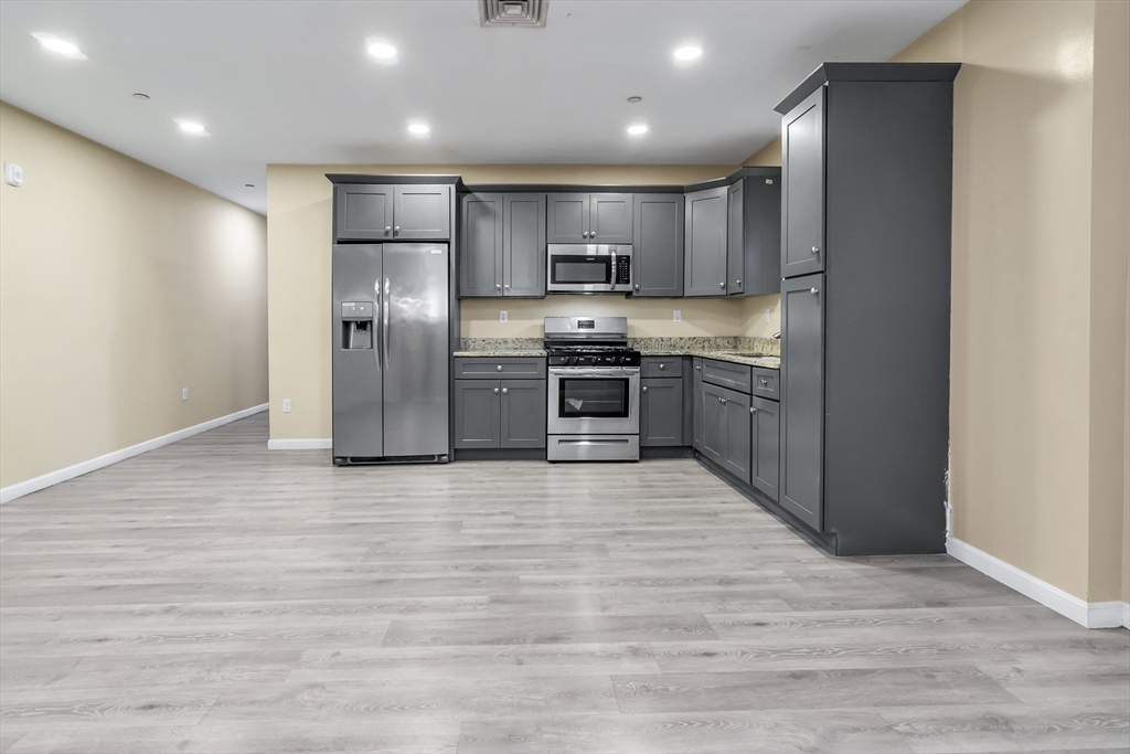 202 Broadway, Unit 23 Lawrence, MA 01840 - Photo 2 of 15 a large kitchen with stainless steel appliances granite countertop a refrigerator and a stove top oven