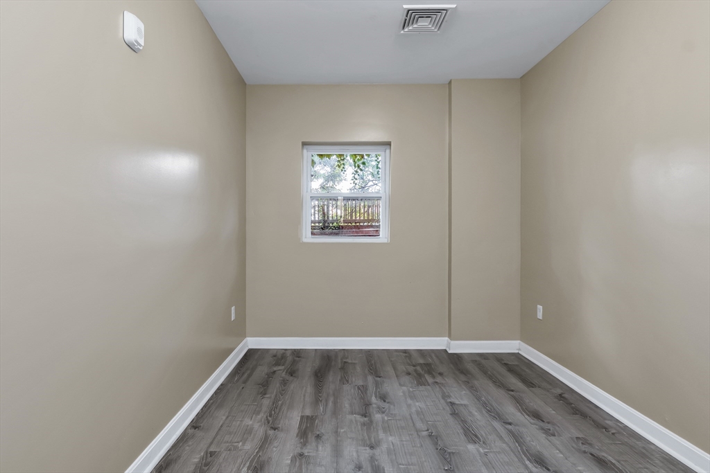 202 Broadway, Unit 23 Lawrence, MA 01840 - Photo 7 of 15 an empty room with wooden floor and windows