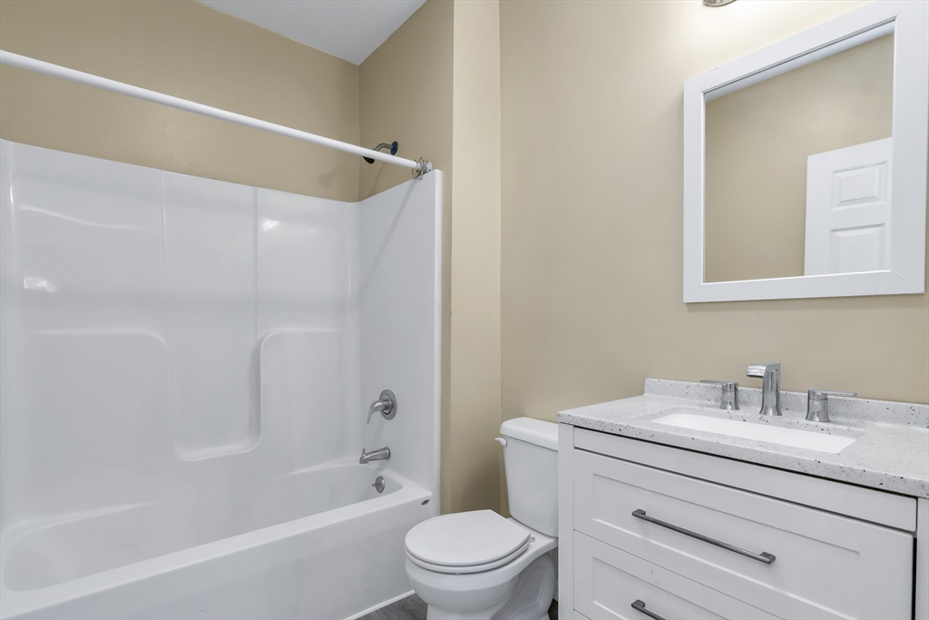 202 Broadway, Unit 23 Lawrence, MA 01840 - Photo 10 of 15 a bathroom with a sink a mirror a toilet and a bathtub