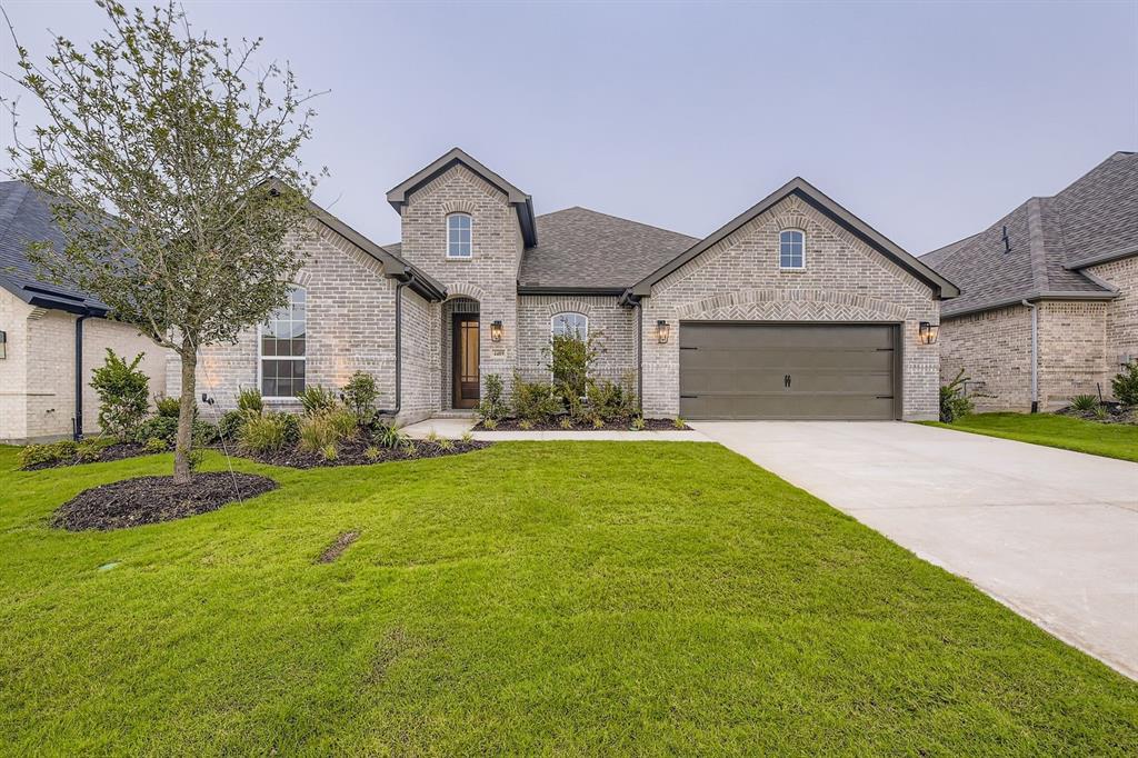 4409 Capstone Road Midlothian, TX 76065 - Photo 1 of 1 French country home with brick siding, driveway, a front lawn, roof with shingles, and an attached garage