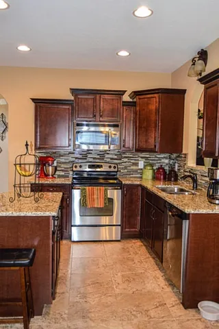 a kitchen with stainless steel appliances granite countertop a stove top oven a sink dishwasher and cabinets
