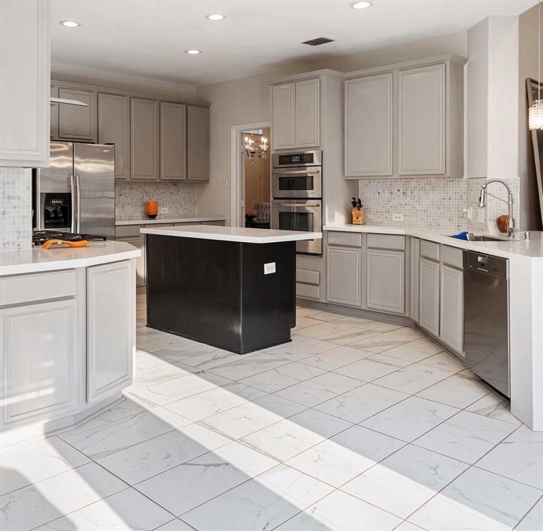 1424 Winston Drive McKinney, TX 75072 - Photo 6 of 28 a kitchen with stainless steel appliances cabinets a sink and a stove