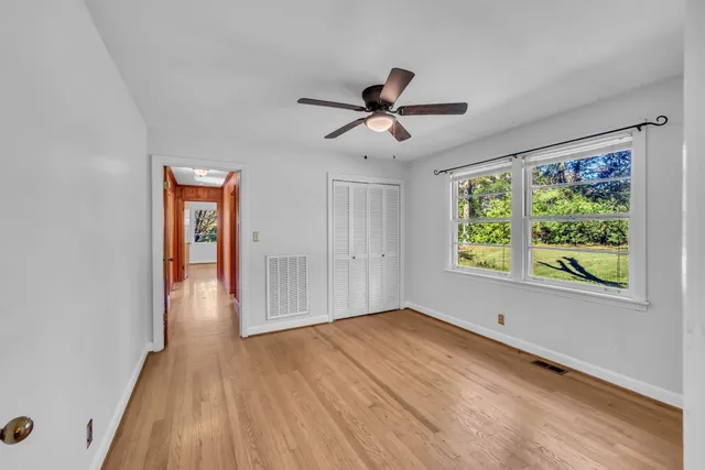 a view of empty room with wooden floor and fan
