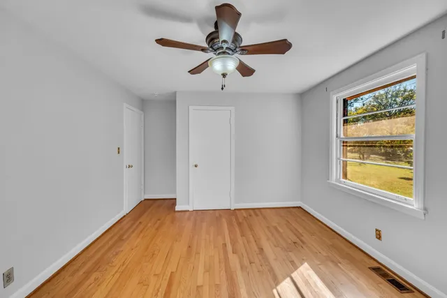 a view of empty room with wooden floor and fan