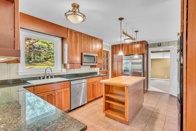 a kitchen with stainless steel appliances granite countertop a sink dishwasher stove and refrigerator with wooden floor