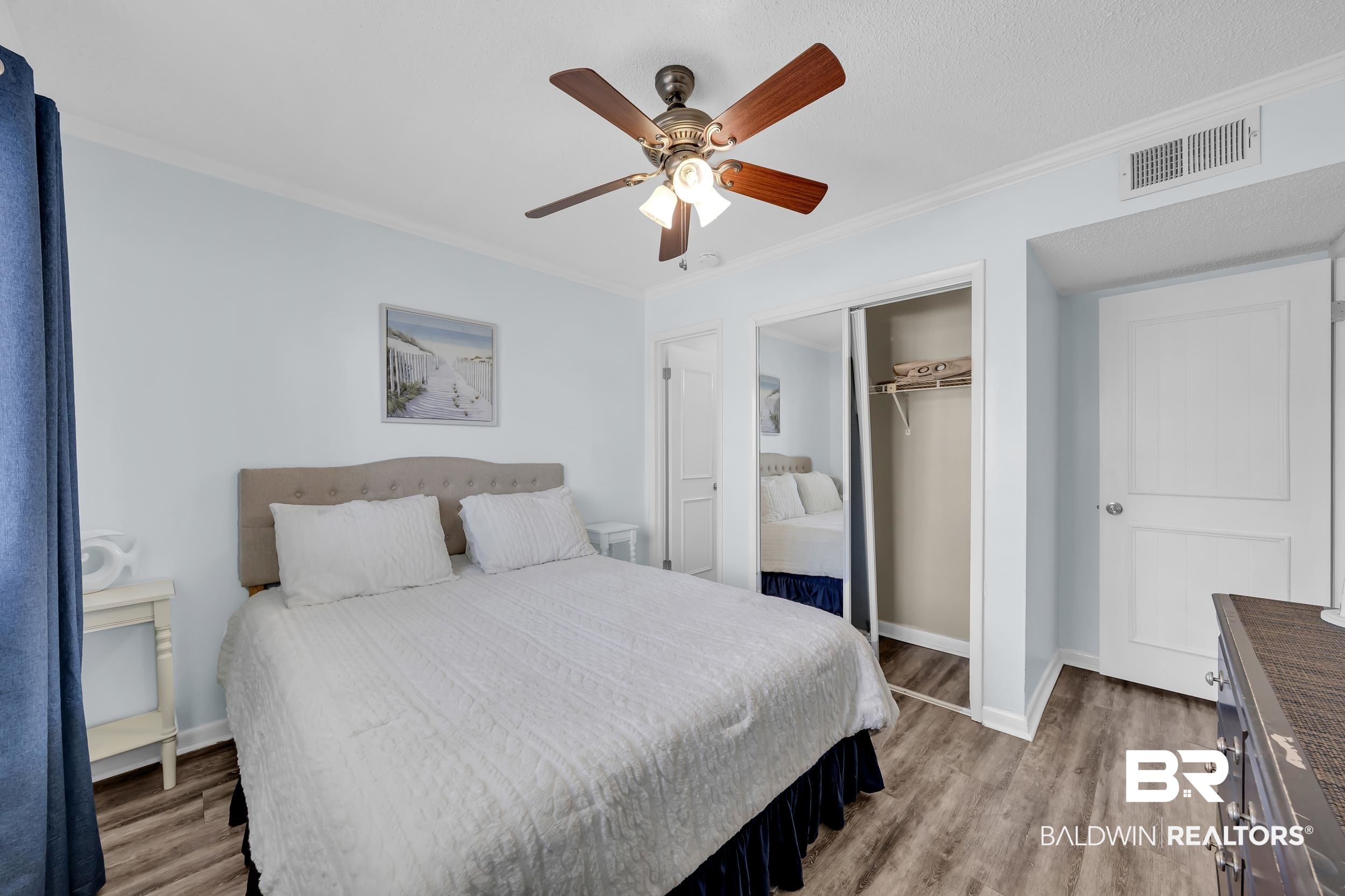 400 Plantation Road, Unit 2118 Gulf Shores, AL 36542 - Photo 15 of 59 Bedroom featuring wood-finish flooring, a ceiling fan with integrated lighting, mirrored sliding closet doors, and a paneled interior door