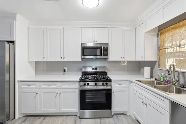 a kitchen with white cabinets and appliances