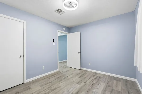 an empty room with wooden floor and a hallway