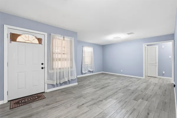 a view of an empty room with wooden floor and a window