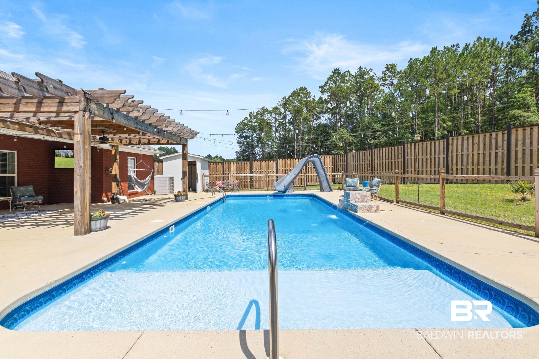 79 Whitetail Run Chatom, AL 36518 - Photo 68 of 82 Rectangular in-ground swimming pool with an attached slide, surrounded by a concrete patio