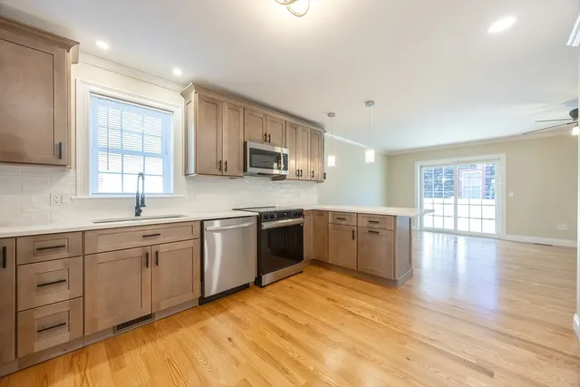 a kitchen with stainless steel appliances granite countertop a refrigerator stove a sink and dishwasher with wooden floor