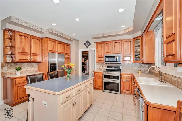 a kitchen with stainless steel appliances granite countertop a stove top oven a sink dishwasher a dining table and chairs with wooden floor