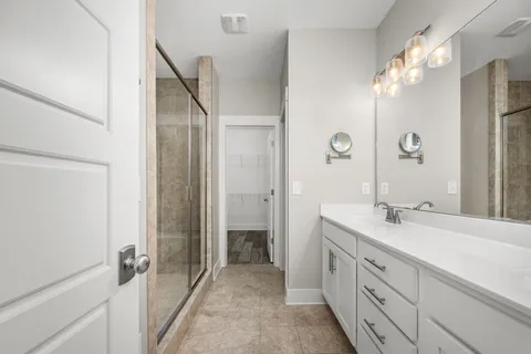 a spacious bathroom with a granite countertop sink a mirror and a shower