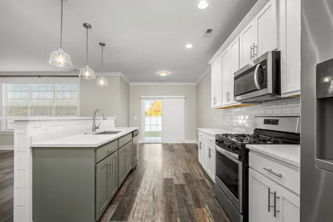 a kitchen with stainless steel appliances kitchen island granite countertop a sink a stove and a wooden floors