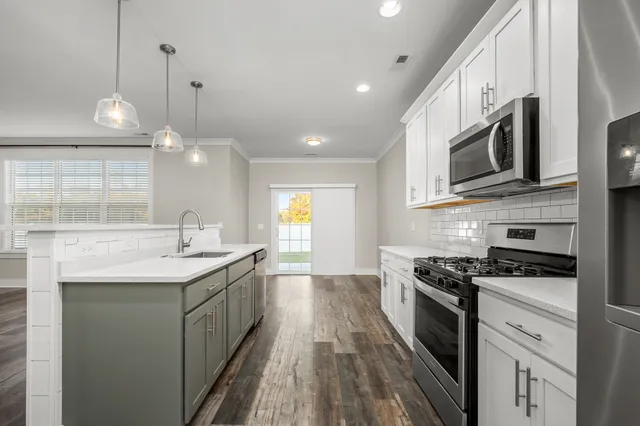 a kitchen with stainless steel appliances kitchen island granite countertop a sink a stove and a wooden floors