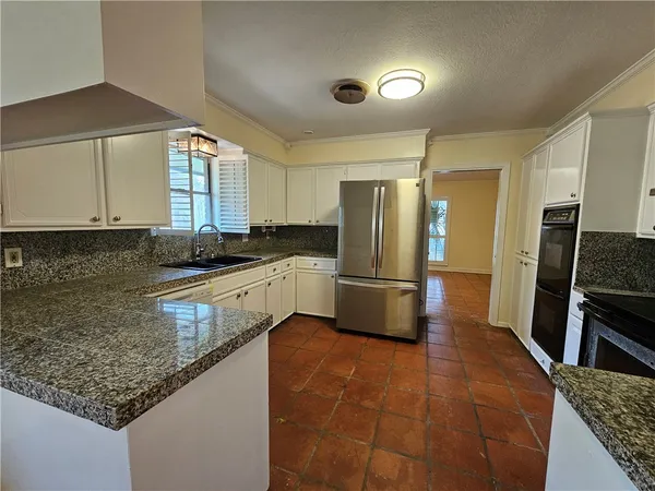 a kitchen with stainless steel appliances granite countertop a sink a stove a refrigerator a washer dryer and white cabinets