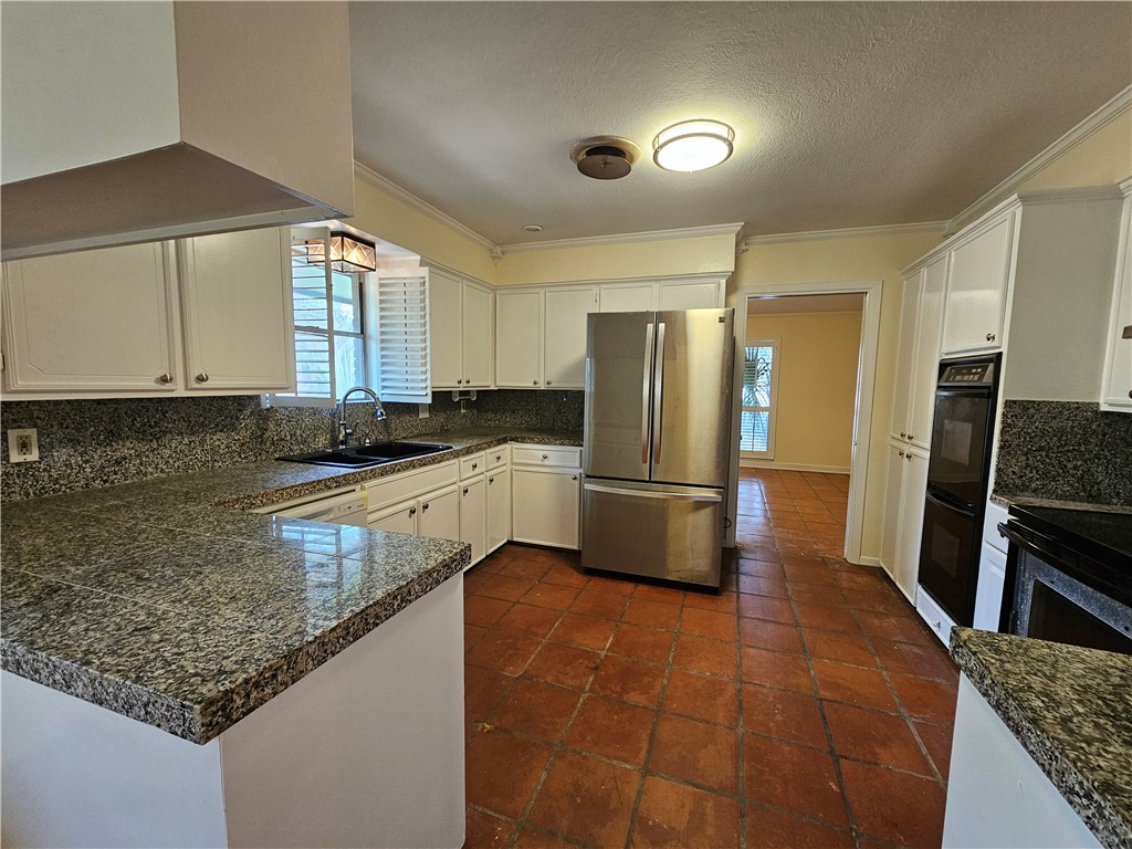 4825 Wooldridge Road Corpus Christi, TX 78413 - Photo 7 of 20 a kitchen with stainless steel appliances granite countertop a sink a stove a refrigerator a washer dryer and white cabinets
