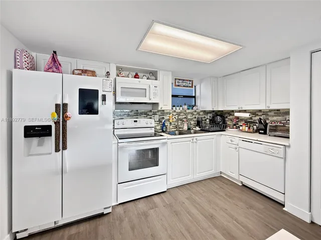 a kitchen with granite countertop white cabinets and white appliances
