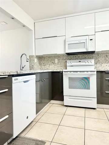 a kitchen with granite countertop a sink cabinets and stainless steel appliances
