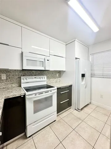 a kitchen with granite countertop a stove top oven and cabinets