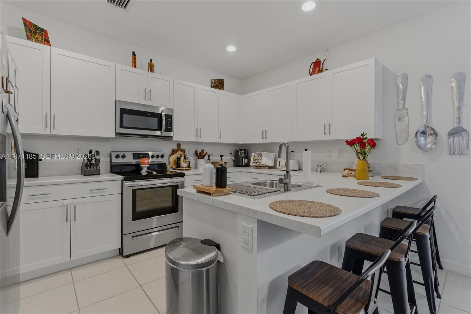 10009 Southwest 228th Terrace Miami, FL 33190 - Photo 10 of 48 a kitchen with a sink a stove and white cabinets