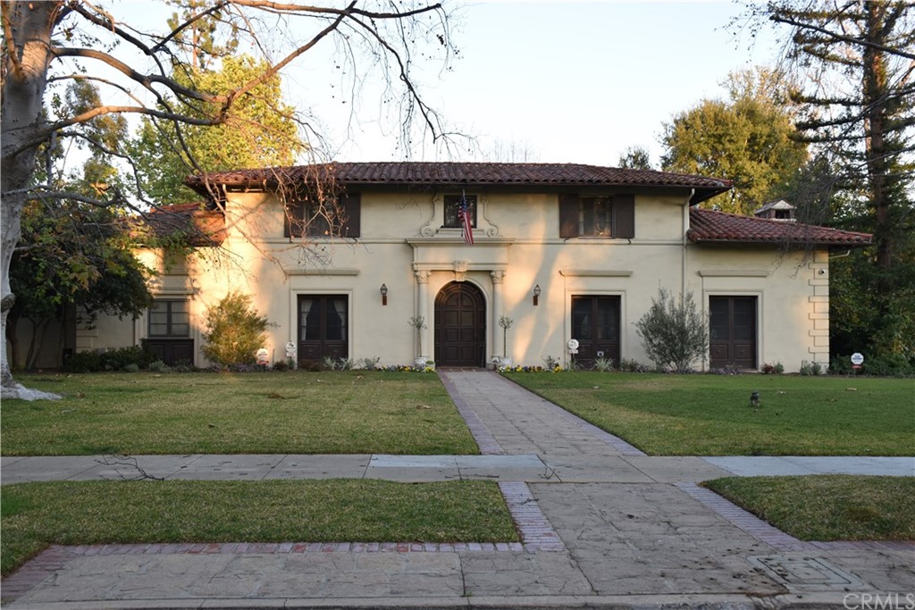 a view of a white house with a yard and large trees