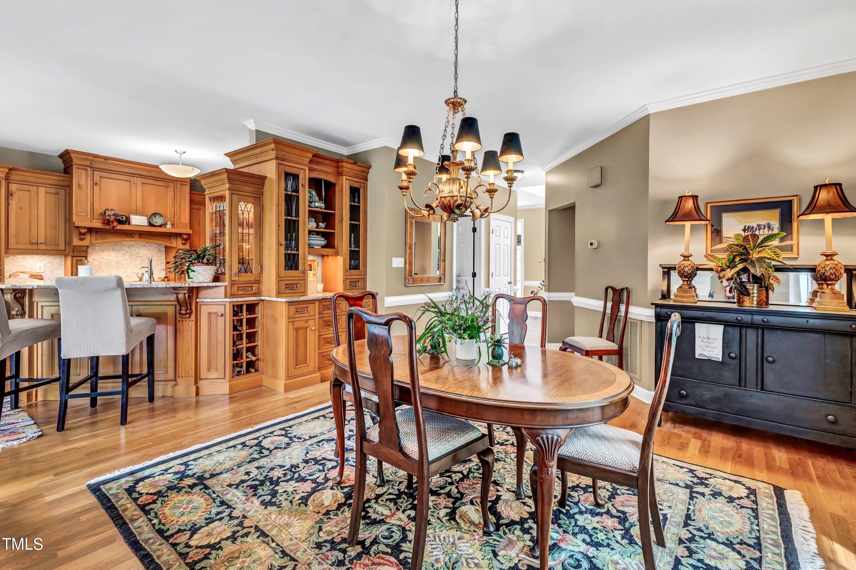 6105 Montcastle Court Raleigh, NC 27612 - Photo 12 of 44 a view of a dining room and livingroom with furniture wooden floor a rug a painting and a chandelier