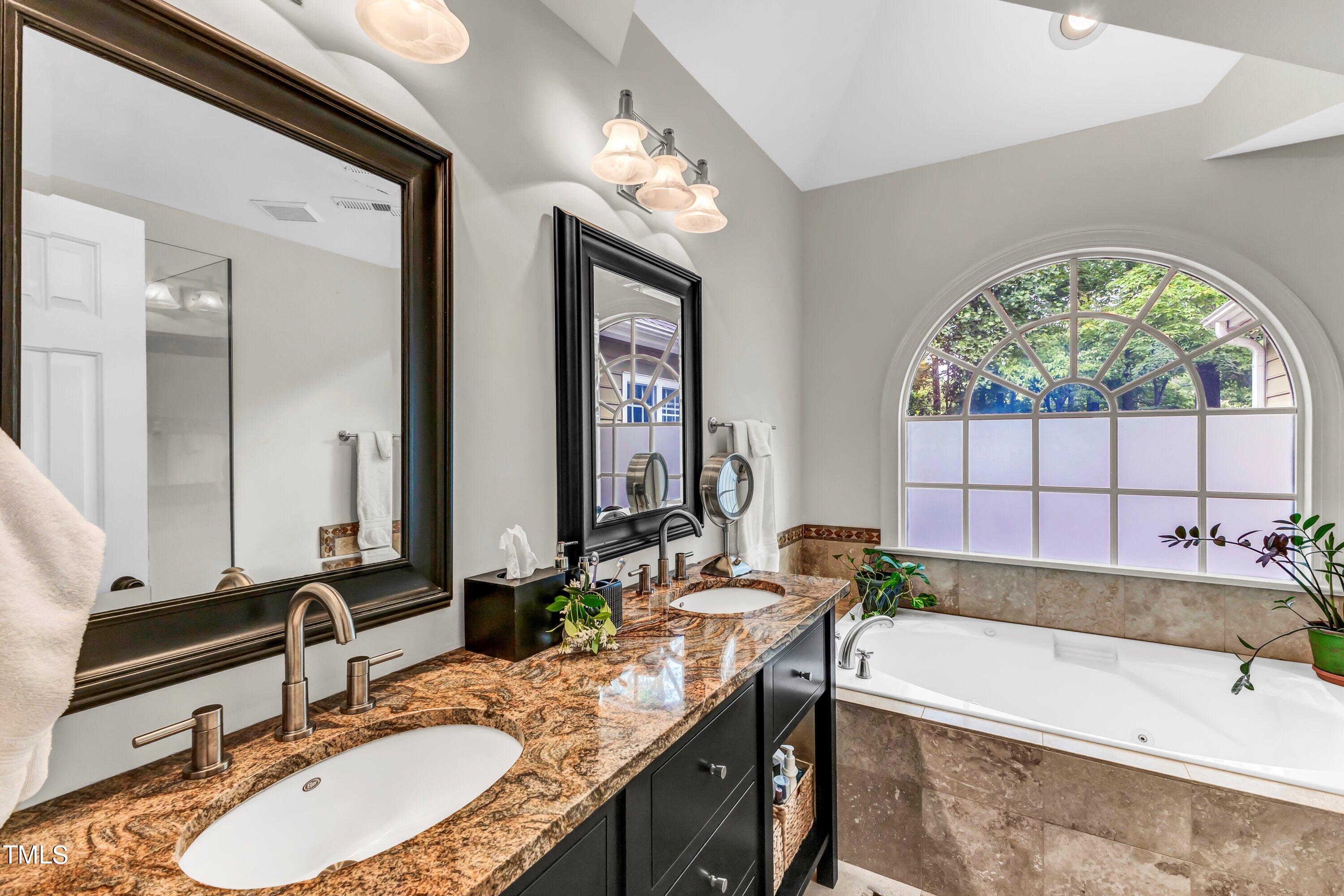 6105 Montcastle Court Raleigh, NC 27612 - Photo 28 of 44 a bathroom with a granite countertop tub a double vanity sink a window and a mirror