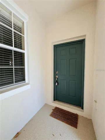 a view of an empty room with window and chandelier fan
