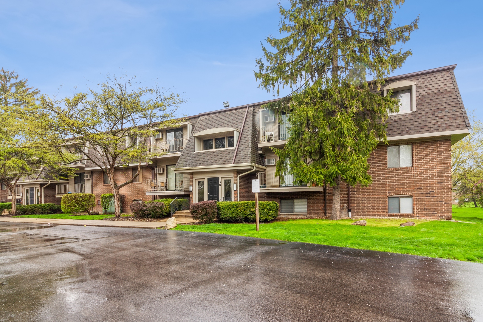 a front view of a house with a garden and trees
