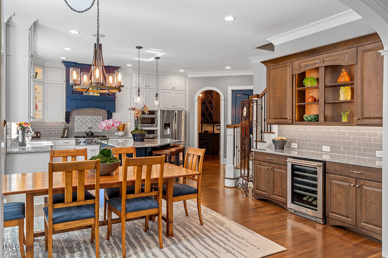 6940 Bartons Bend Way Raleigh, NC 27614 - Photo 19 of 66 a kitchen with stainless steel appliances granite countertop a stove a refrigerator a kitchen island a dining table and chairs with wooden floor