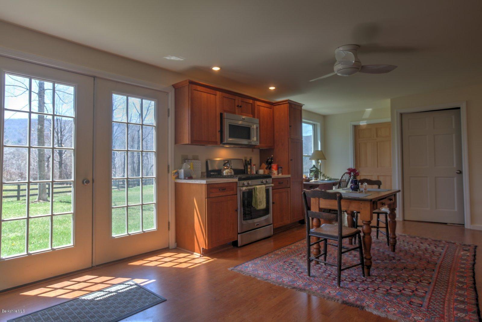 20 Main Road Tyringham, MA 01238 - Photo 39 of 50 a kitchen with stainless steel appliances granite countertop a stove top oven a sink a dining table and chairs