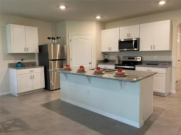 a kitchen with kitchen island a white counter top space cabinets and stainless steel appliances