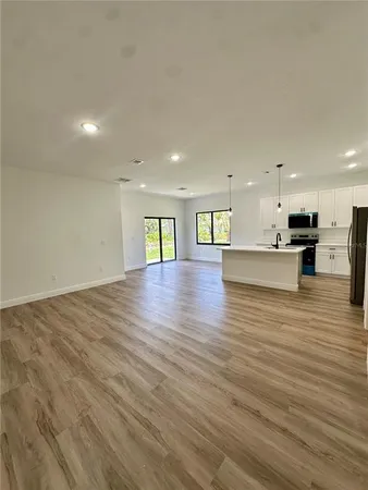 a view of an empty room with kitchen view and a counter top space
