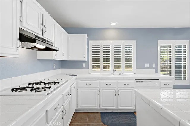 a large white kitchen with sink and white cabinets