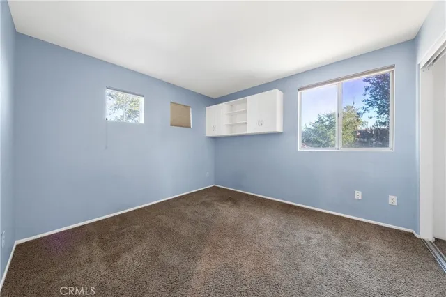 an empty room with windows and air conditioner vent