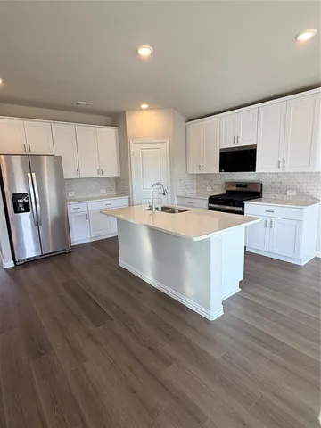 a large kitchen with stainless steel appliances wooden floors and wooden cabinets