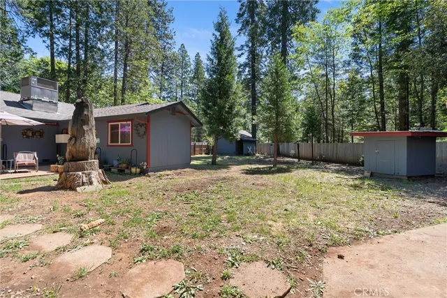 a view of a backyard with large trees and wooden fence