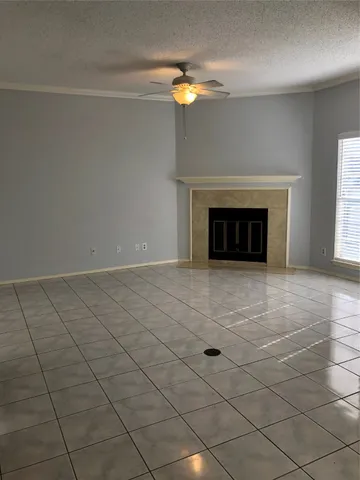 an empty room with a fireplace and chandelier fan